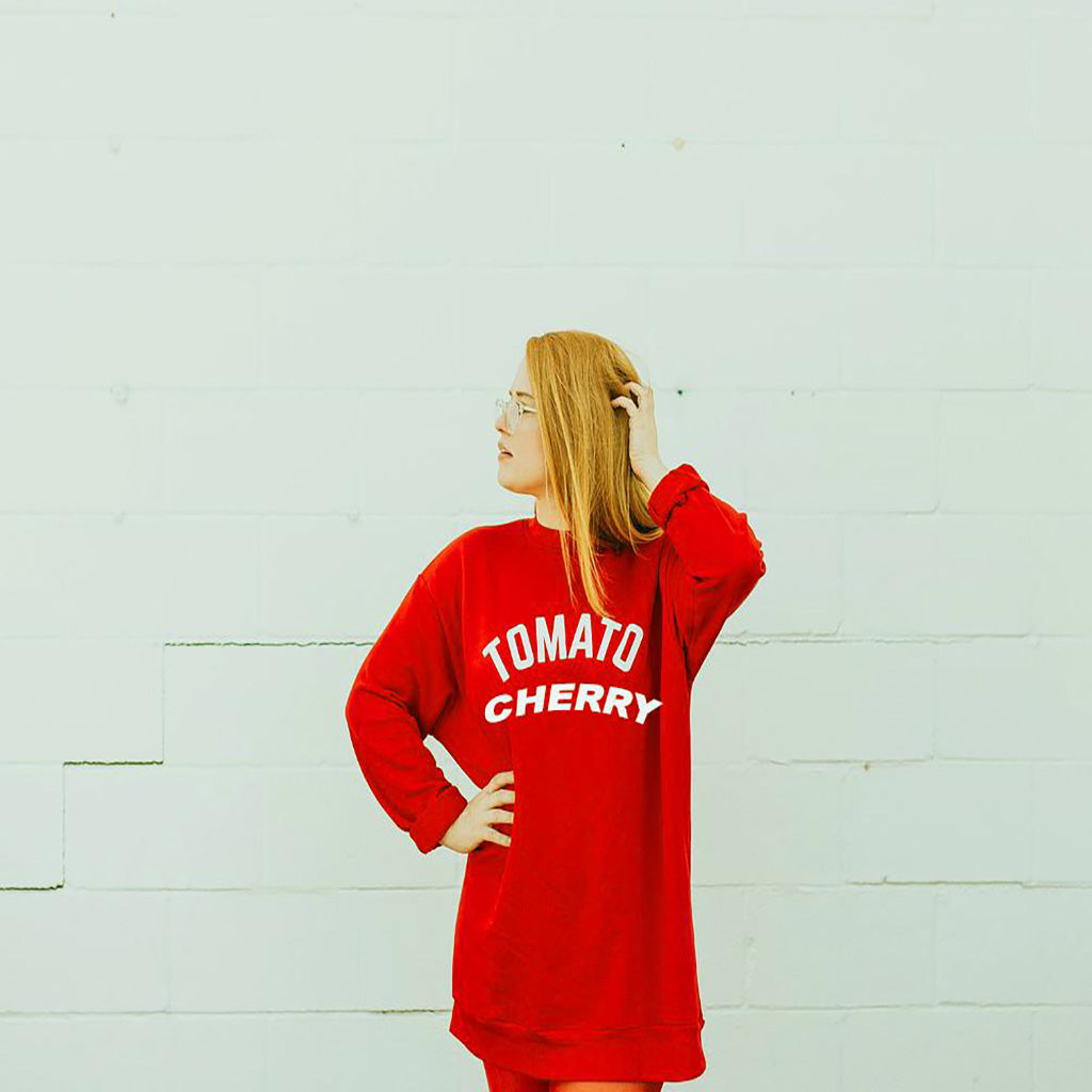 Girl with a orange/red sweat sweater against white wall